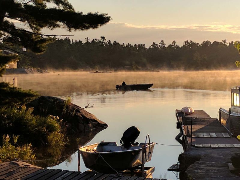 Sunrise over a lake and a fisherman returning to the dock
