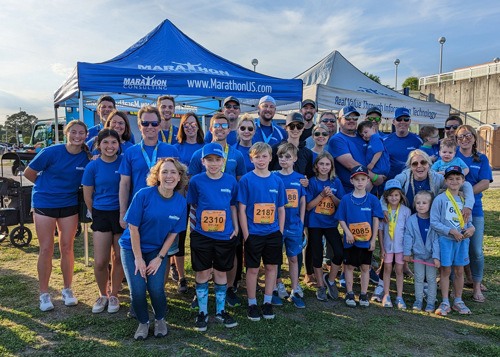Marathon Consulting team group photo in blue t-shirts with family